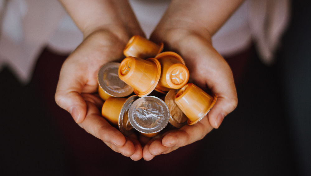 A pair of hands holding orange plastic pods (Photo by Kous9 on Unsplash)