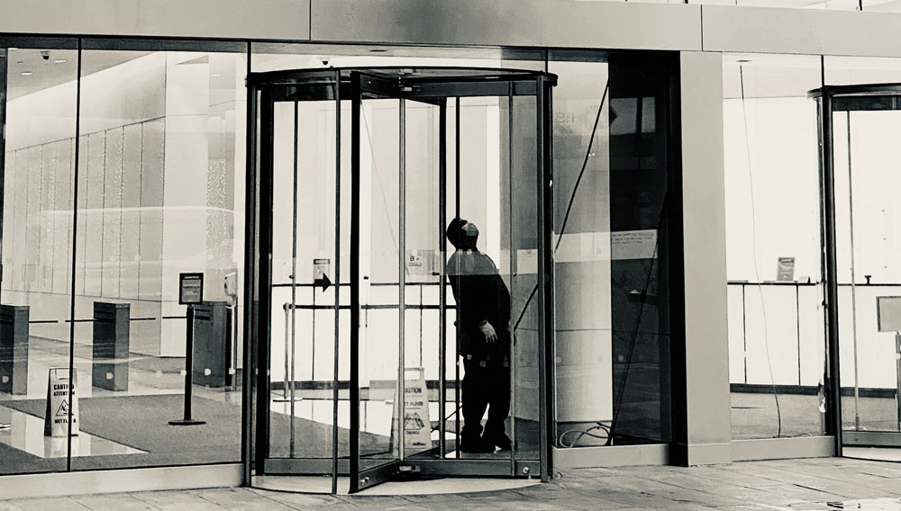 A man standing between revolving doors (Photo by Jon Tyson on Unsplash)