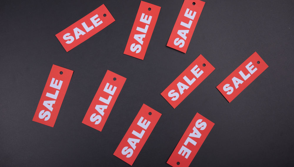 Nine red sale stickers on black board (Photo by Tamanna Rumee on Unsplash)