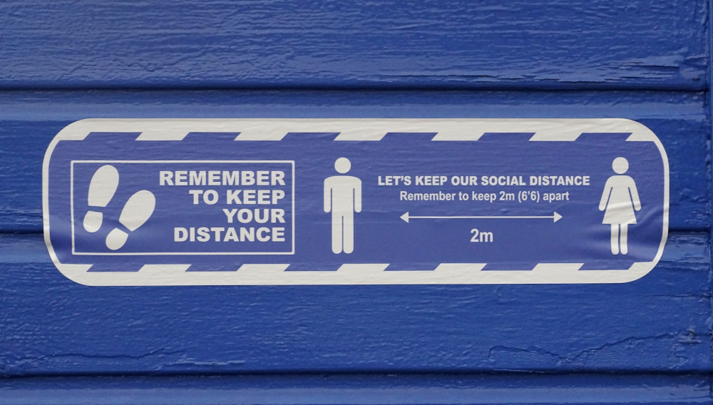 Blue sign: Remember to keep your distance (Photo by Belinda Fewings on Unsplash)
