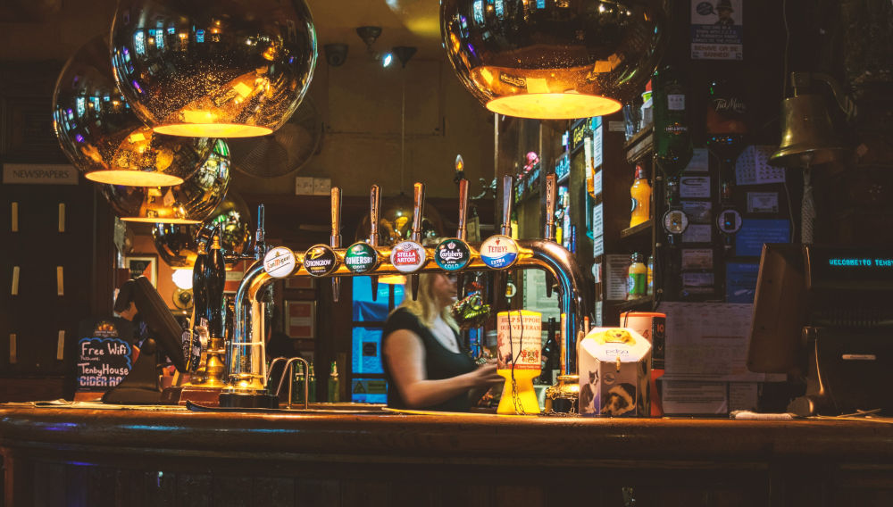 View of a bar with taps in the front serving well-known beer brands by Big Brewers (Photo by Matthieu Comoy on Unsplash)