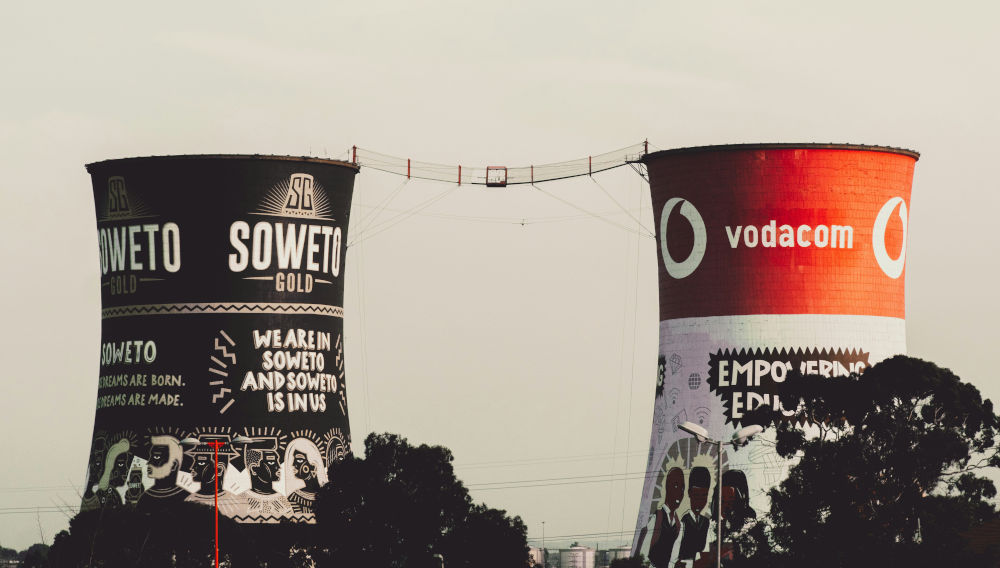 Two towers with banners on them, Soweto, South Africa (Photo: Robin Kutesa on Unsplash)