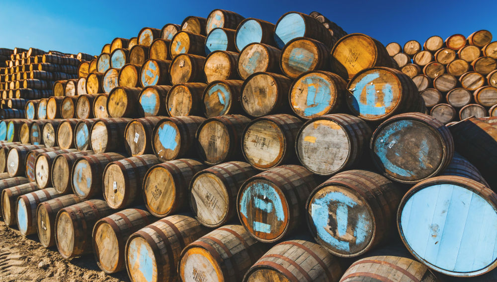 Large stack of wooden barrels in front of a blue sky (Photo: Brian Taylor on Unsplash)