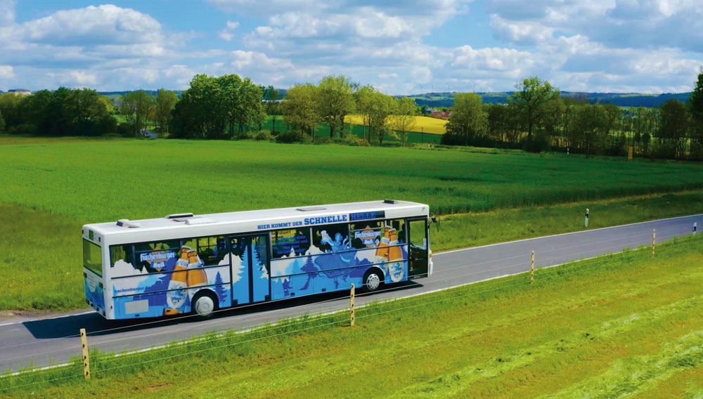 Ein Bus mit Werbeaufdruck der Westerwald-Brauerei und Schriftzug der schnelle Helle fährt auf einer Landstraße