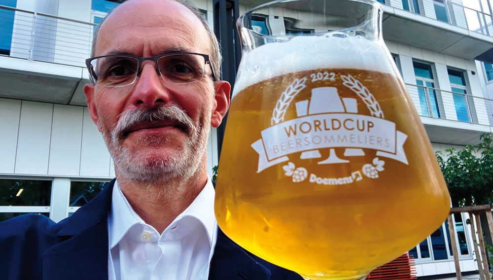 Markus Fohr mit dem World Cup Glas 2022 vor dem Ort des Geschehens, dem neuen Doemens Gebäude in der Lohenstraße in Gräfelfing