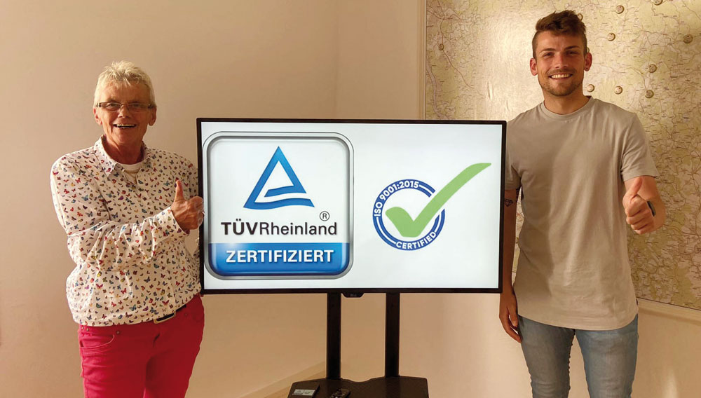 Die beiden Projektleiter Carmen Müller und Sven Bernhard mit dem Zertifikats-Logo ISO 9001