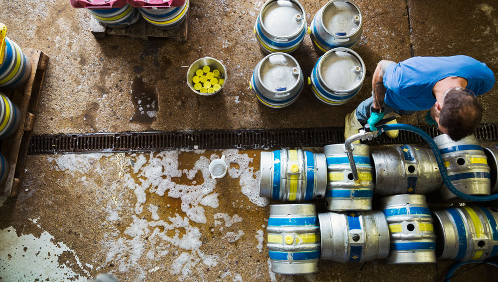 Mitarbeiter füllt Kegs in der Brauerei ab (Foto: Getty Images / Mint Images)