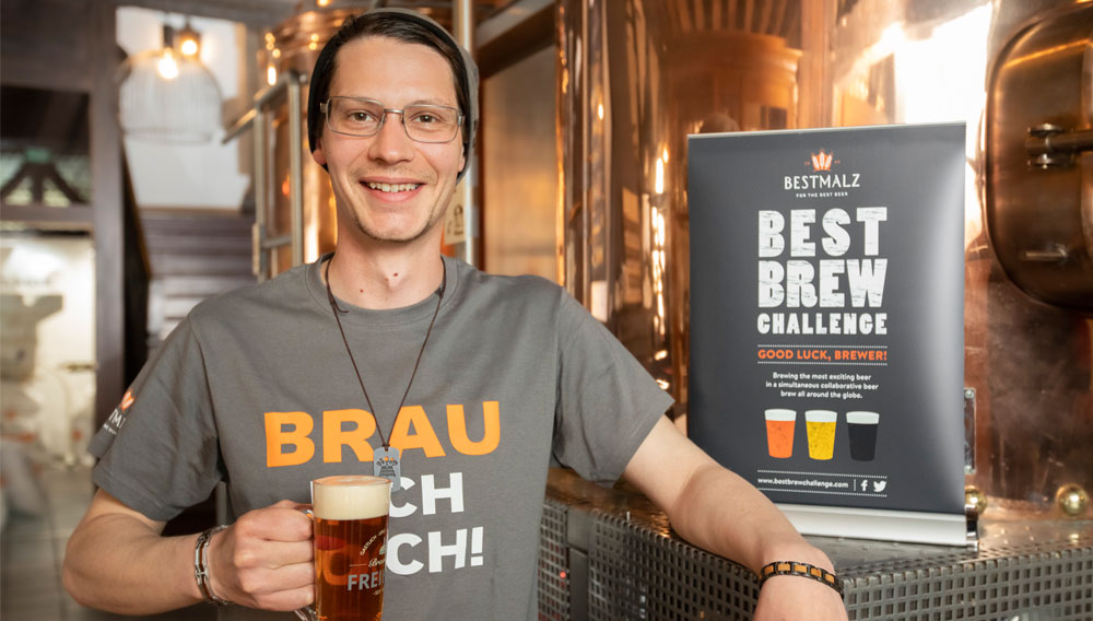 Brauer mit Bier vor dem BestBrewChallenge-Banner (Foto: BESTMALZ/Gerhard Kopatz)