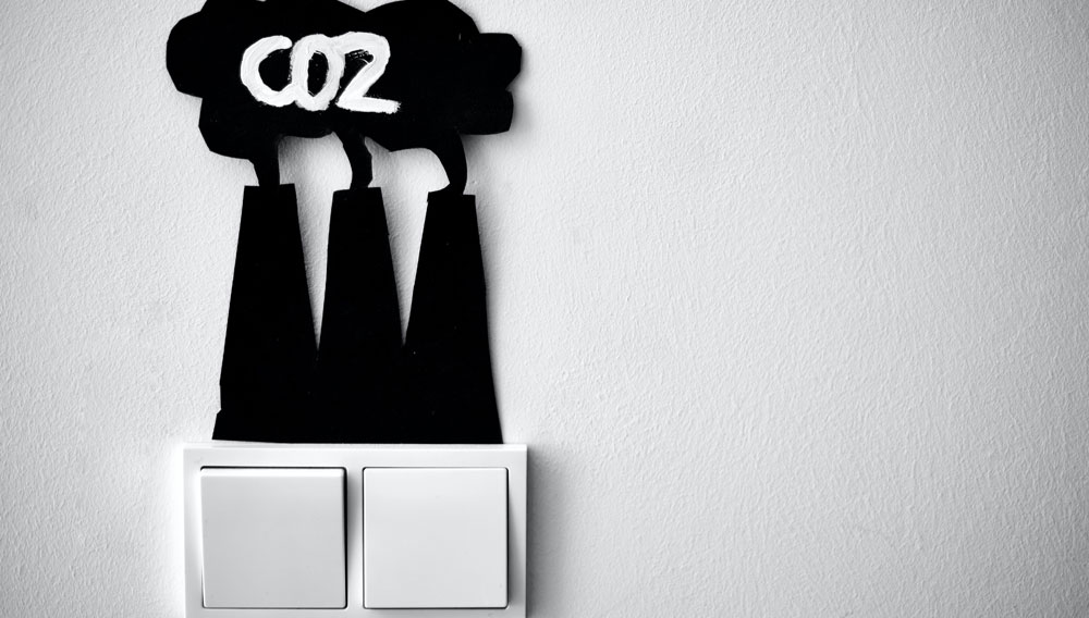 Lichtschalter mit Kraftwerkmotiv mit Rauchwolke und Beschriftung „CO2“ (Foto: Jasmin Sessler auf Unsplash)