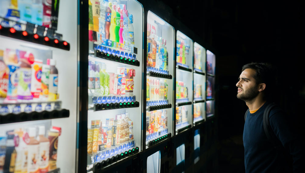 Mann betrachtet Verbrauchsautomaten mit Getränken