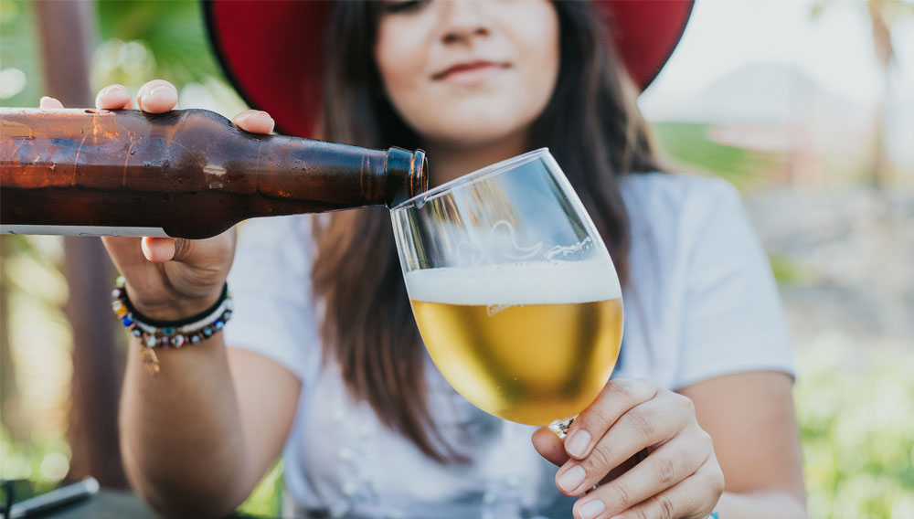 Frau schenkt Bier in ein Glas ein (Maria Benitez auf Unsplash)