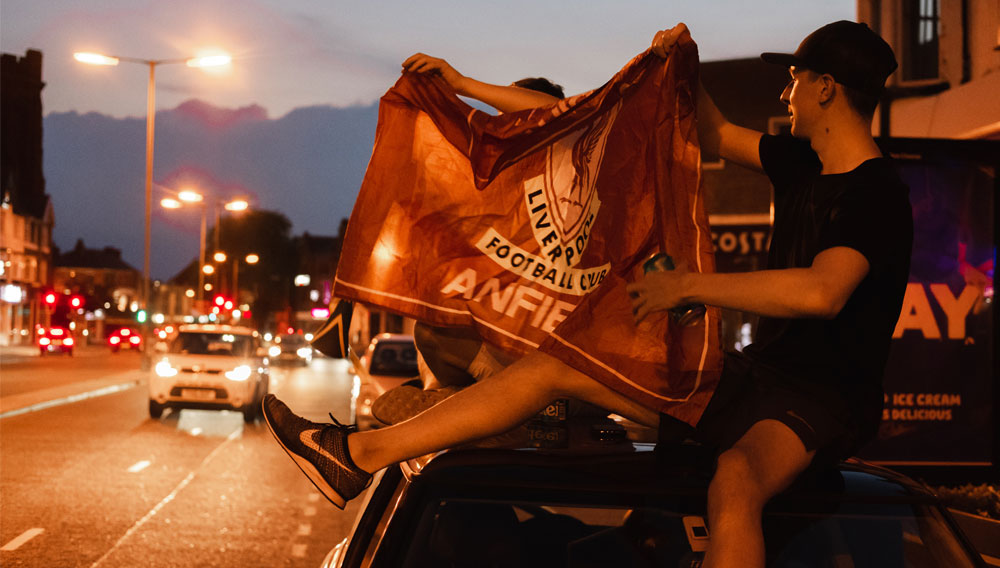 Fußballfan mit Liverpool-Flagge an einer Straße
