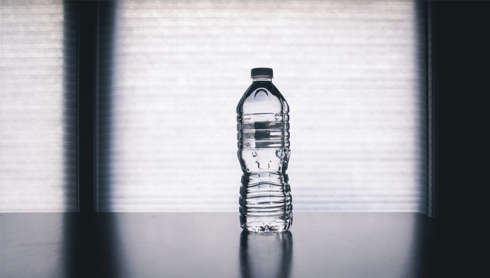 Eine PET-Flasche mit Wasser auf einem Tisch (Foto: Steve Johnson auf Unsplash)