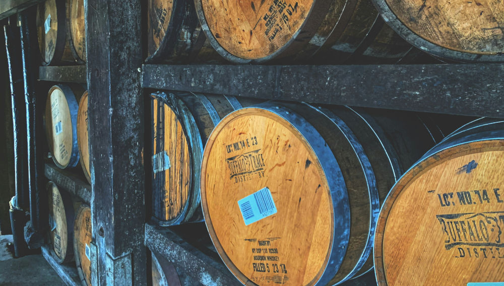 Holzfässer in Regalen (Foto: Josh Collesano auf Unsplash)