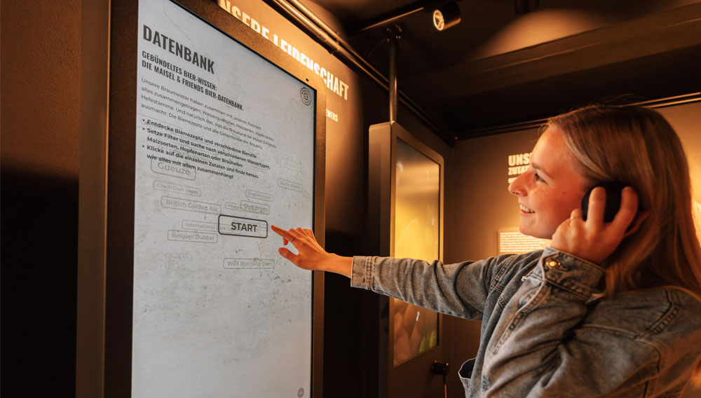 Frau steht an einem interaktiven Bildschirm