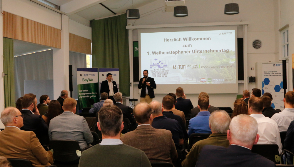 Menschen in einem Vortragsraum hören zwei Rednern zu'