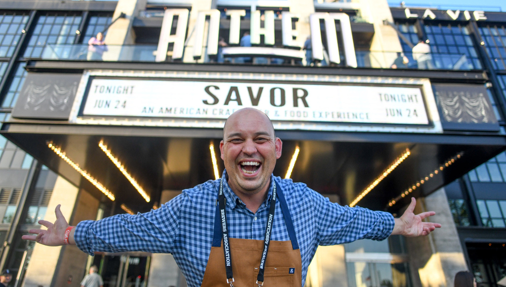Mann breitet die Arme vor dem Eingang von Savor aus