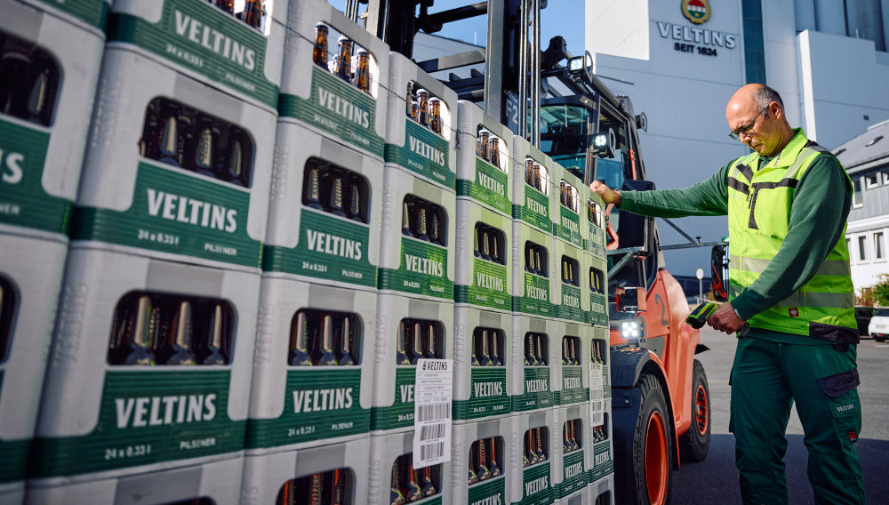 Logistik-Mitarbeiter scannt eine Palette mit Bierkästen (Foto: Veltins)