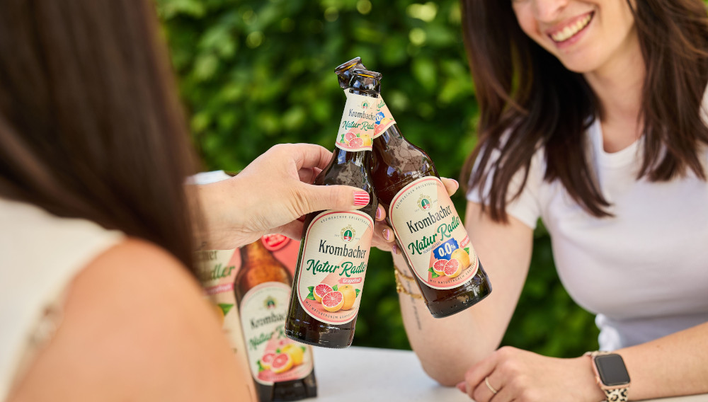 Zwei Frauen stoßen mit Krombacher NaturRadler Grapefruit an