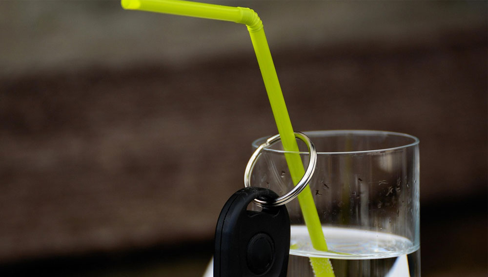 Wasserglas mit Strohhalm, an dem ein Autoschlüssel hängt (Foto: Congerdesign auf Pixabay)